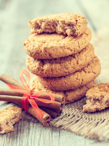 a stack of oat flour cookies and a bundle of cinnamon sticks tied with a red ribbon