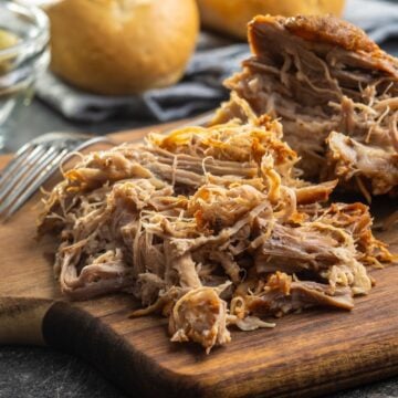 A cutting board with tender, juicy pulled pork